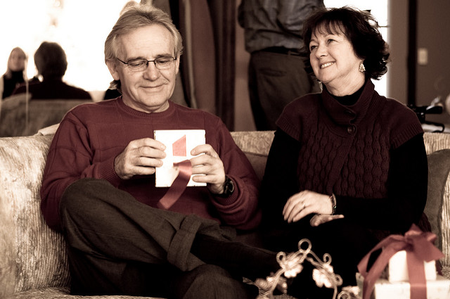 Older couple sitting on the couch opening gifts.
