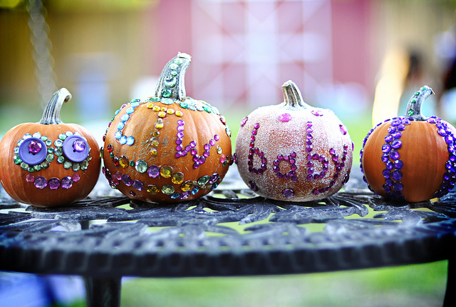 A group of four small pumpkins decorated with glitter and jewels.