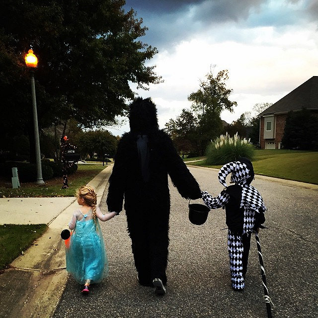 An adult and two children dressed up for Halloween trick-or-treating.