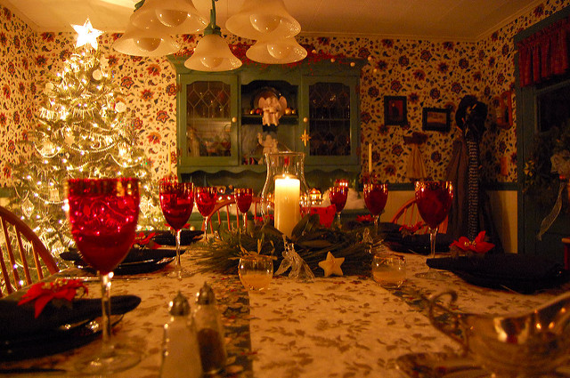 A decorated dining room with a Christmas tree and table set for a holiday meal.