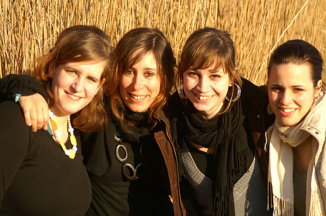 A group of four smiling women in embrace.