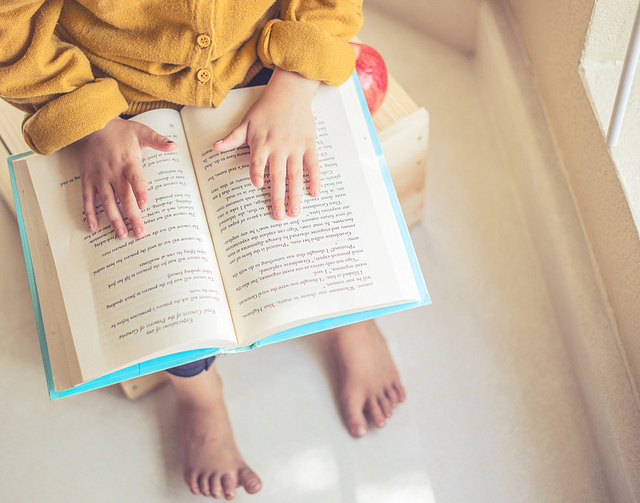 Close-up image of an open book in a child's lap.