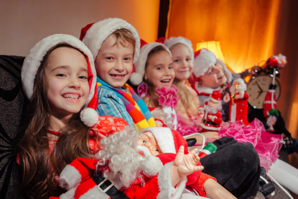 A group of adopted children in santa hats smile with their toys