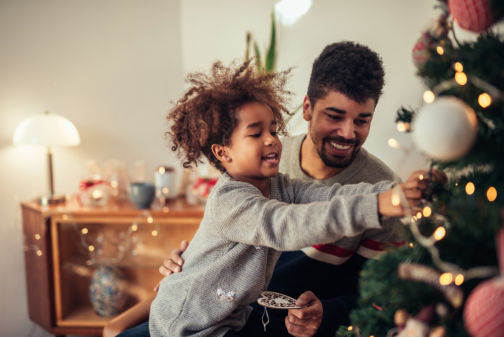 Child and dad decorate a Christmas tree together