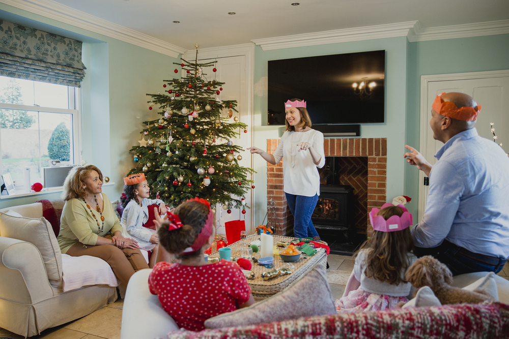 A family plays charades in front of the christmas tree