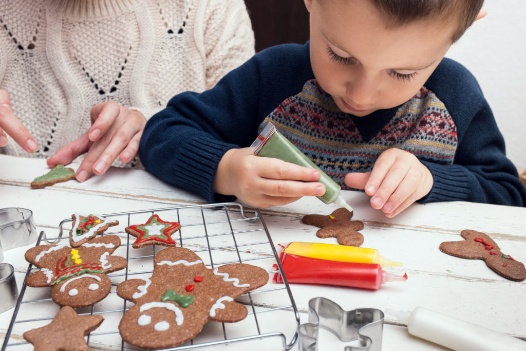 Child decorates gingerbread cookie with icing 