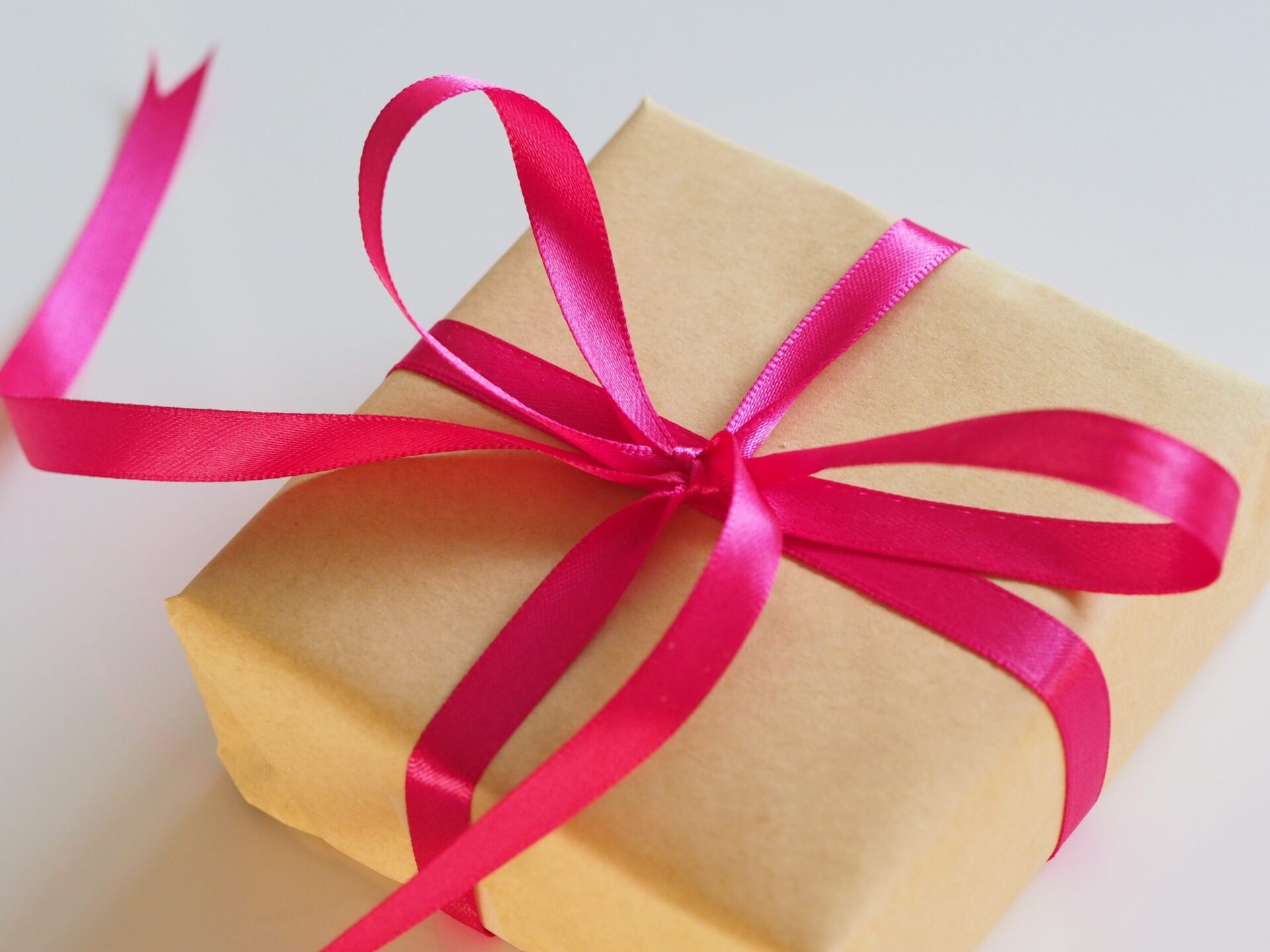 A square box wrapped in brown paper and pink ribbon.