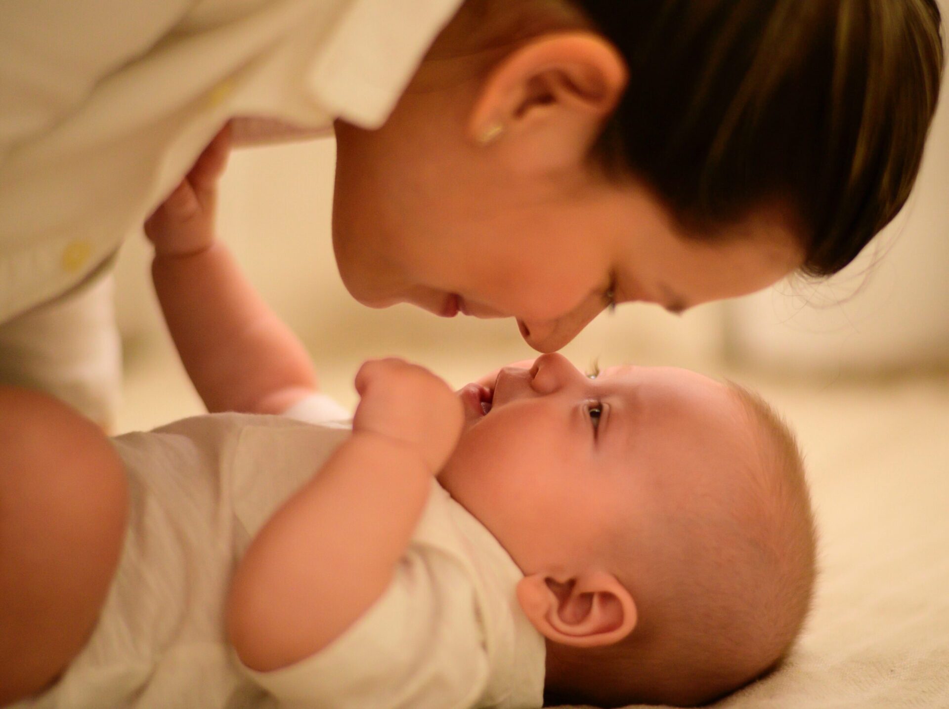 Woman holds her nose up to a baby's nose.