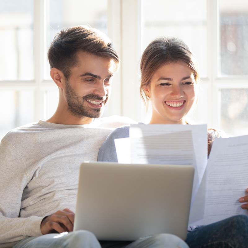 A man and woman sit with a laptop and papers.