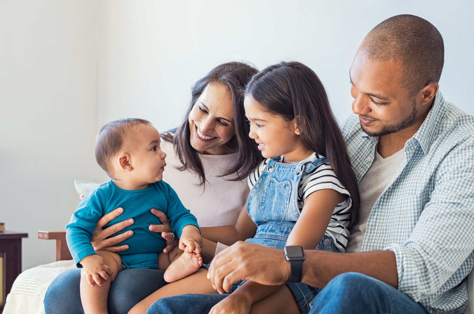 a family of 4 sits on a couch