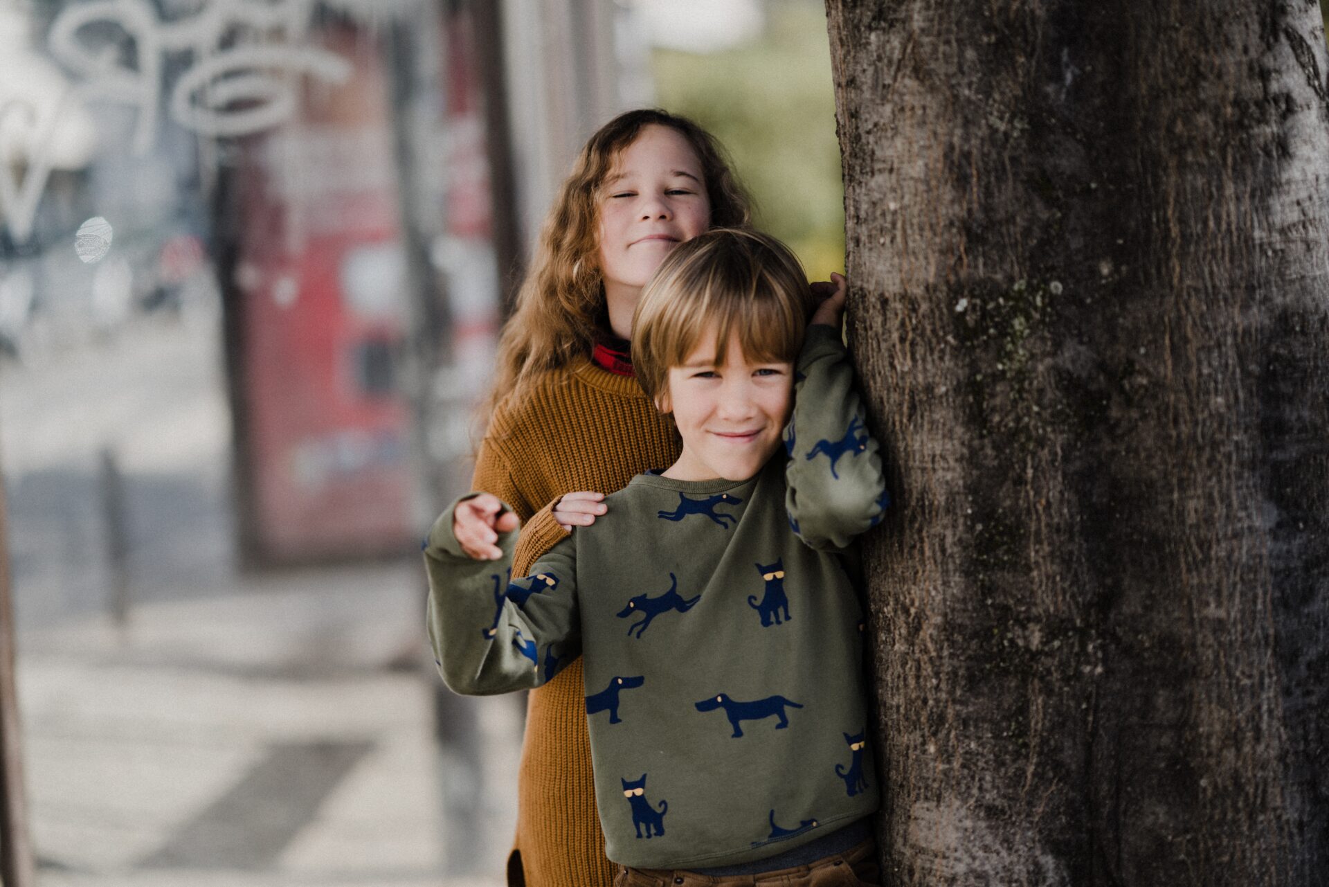 Two children posing next two a tree.
