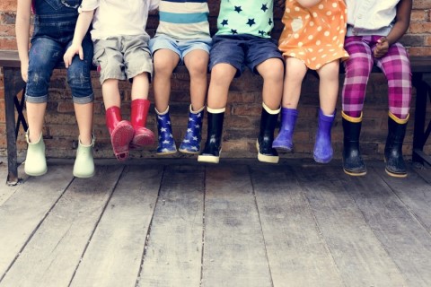 children sitting on a bench with rubber boots on