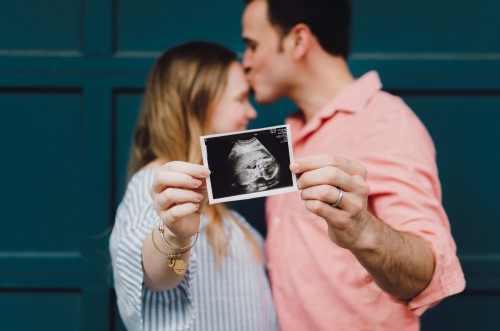 parents holding up ultrasound of their child