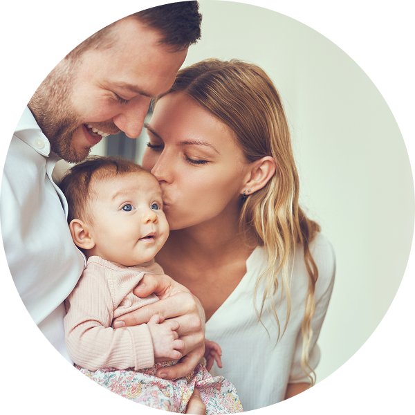 Color image in a circular frame of an infant's hand being held by an adult's hands